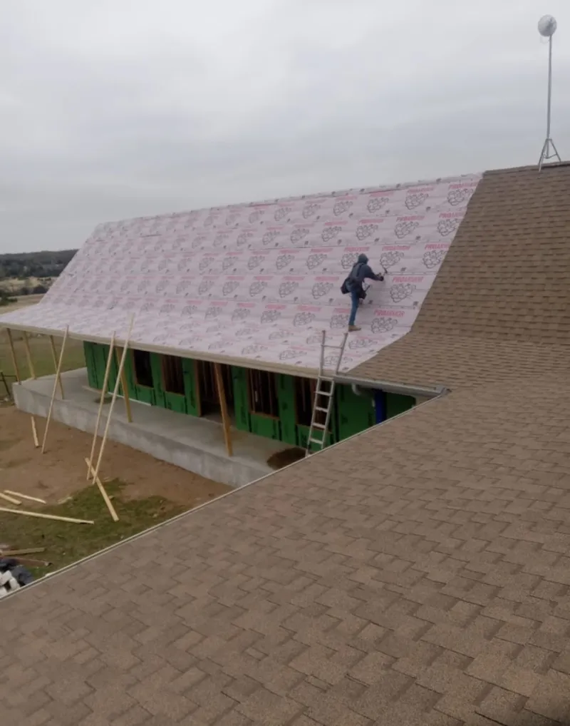 Worker preparing underlayment for a metal roof installation in Edwards